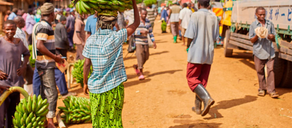 People carrying food down a path in a town