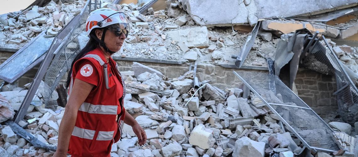 Humanitarian worker walking past demolished building