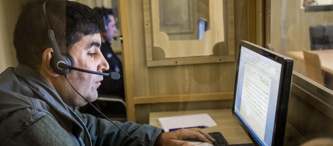 A man with headset sitting in front of a computer