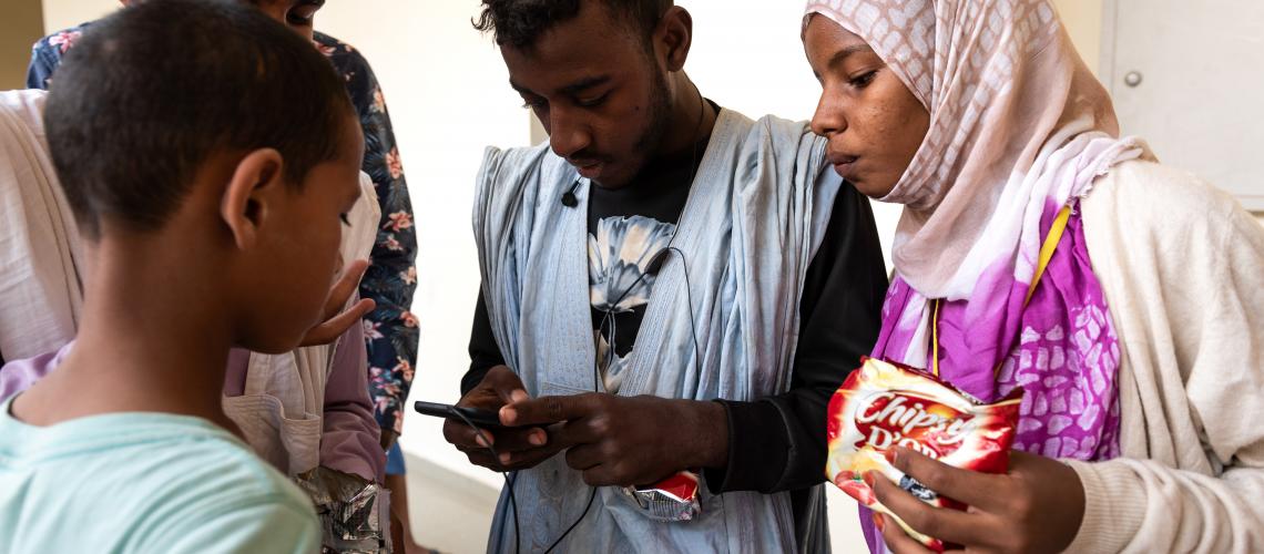 A group of young people looking at a mobile phone